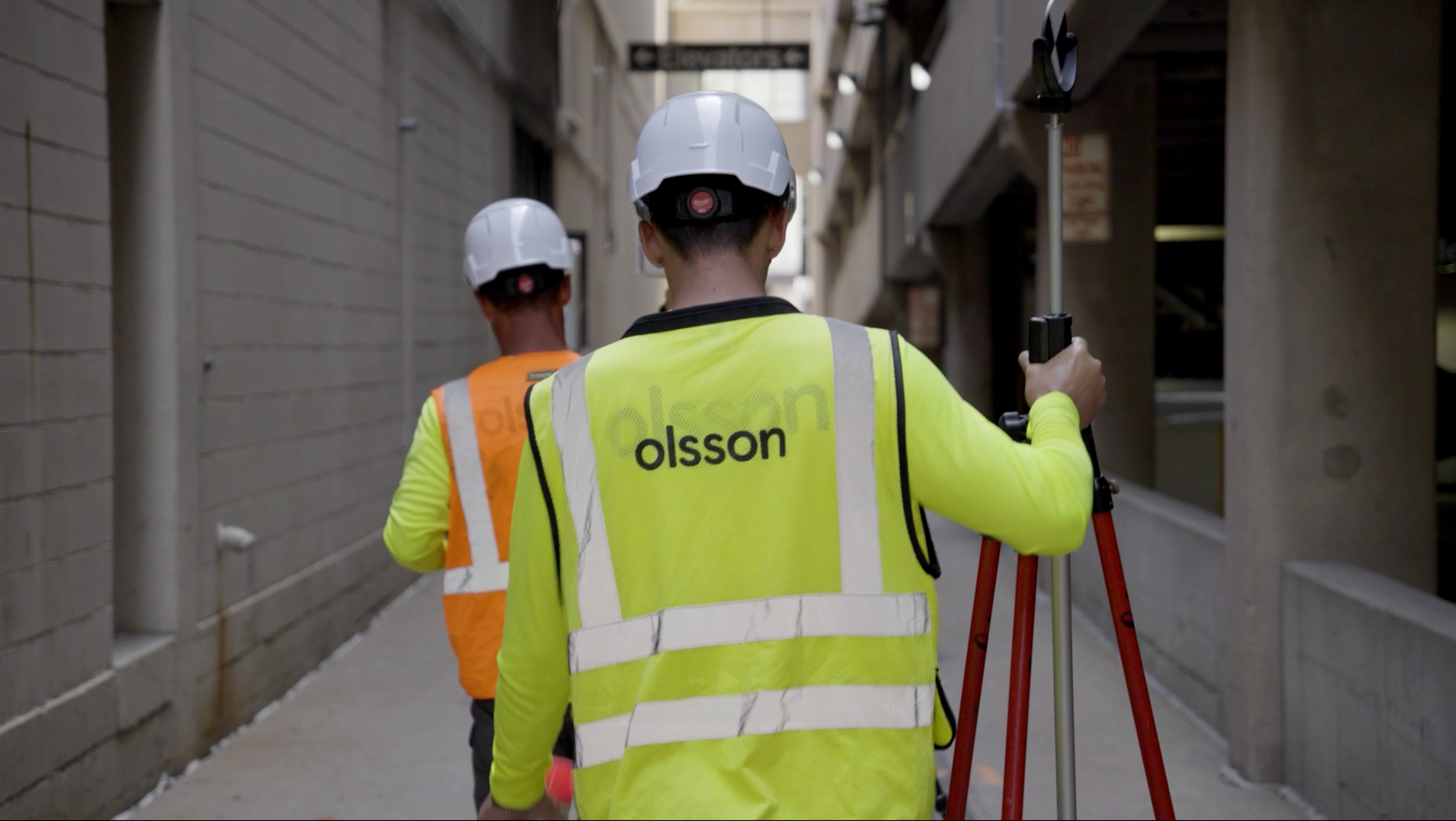 Two Olsson surveyors from behind, walking a street