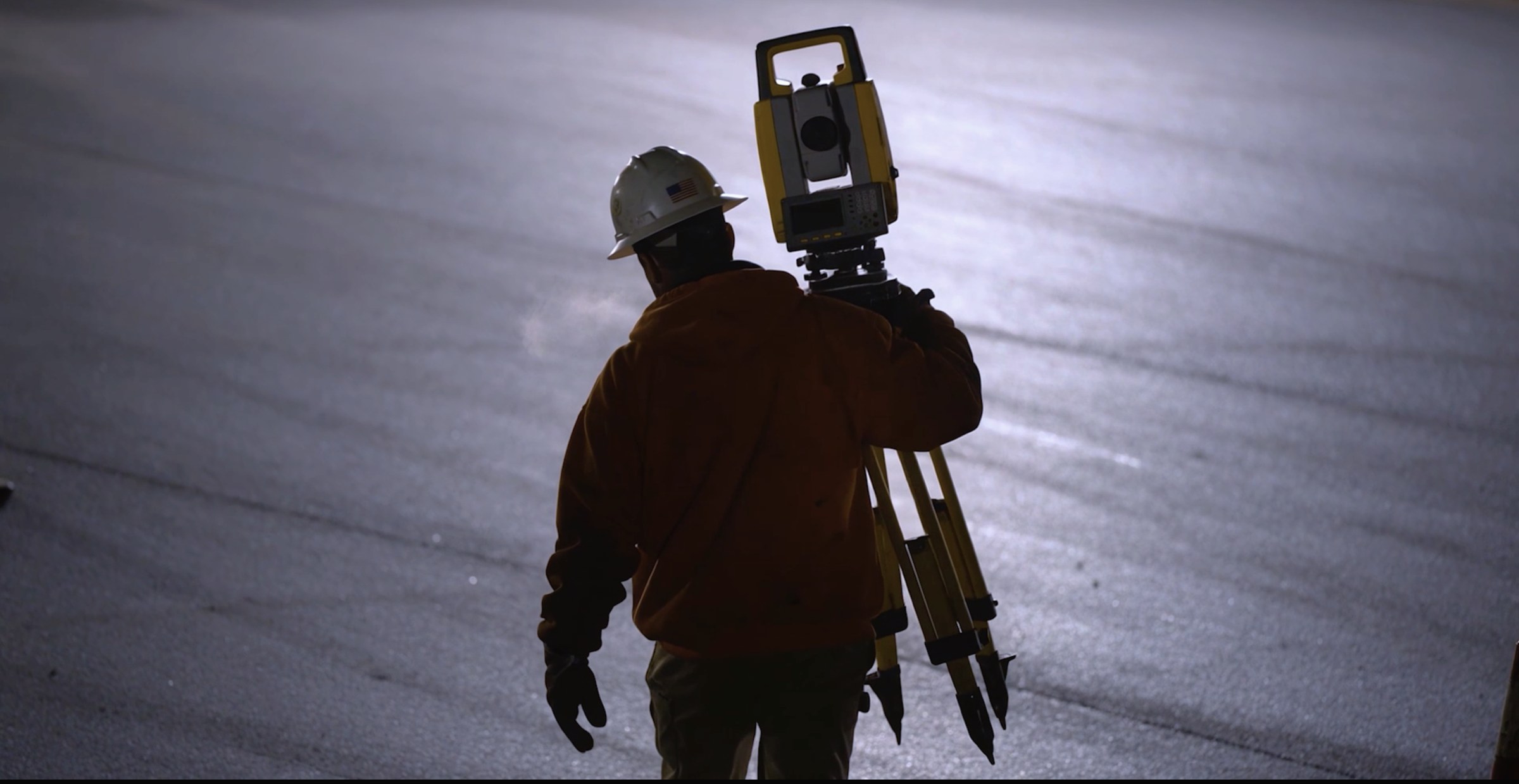Surveyor silhouetted against the sky with a total station