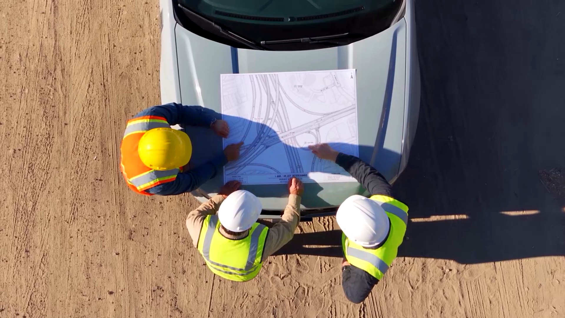 Crew reviewing plans on a truck hood, from above