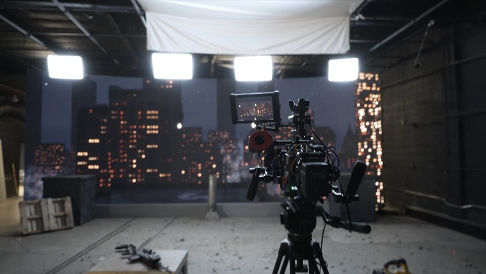 Camera facing a night-city backdrop on a stage