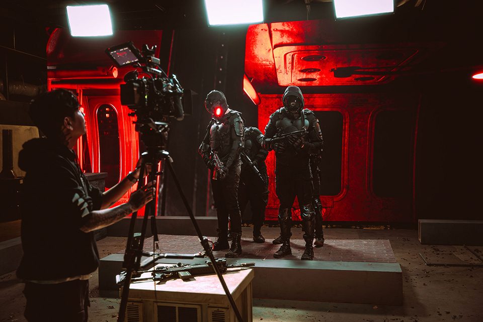 Crew filming on a red-lit stage set