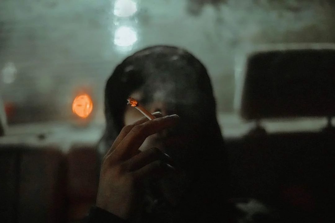 Figure smoking in a dark back seat