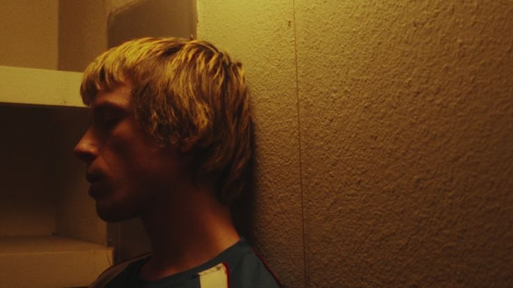 Young man leaning against a wall in yellow light