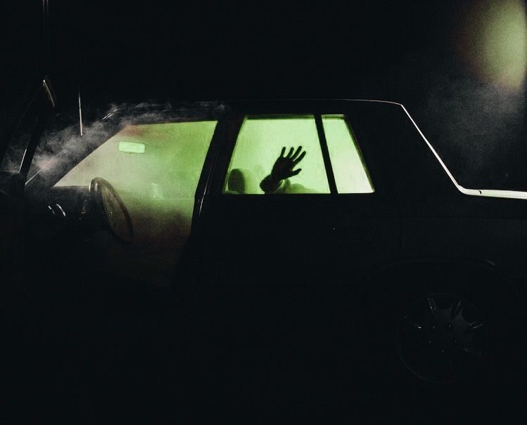 A hand pressed against a glowing car window
