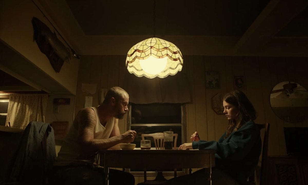 Two people at a kitchen table under a stained-glass lamp