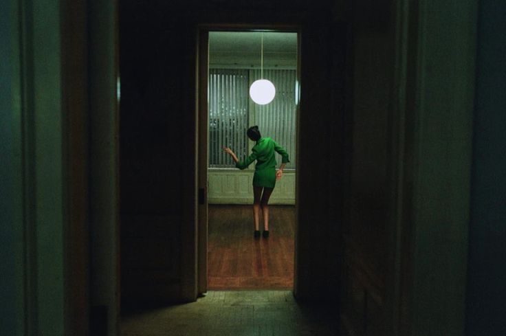 Figure in green seen through a dark doorway