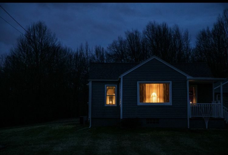 House at dusk, one warm window lit