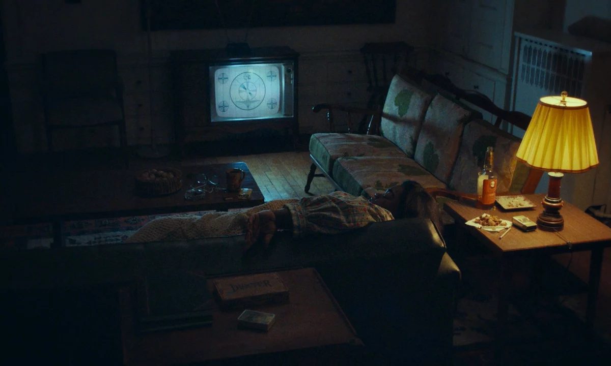 Dim living room lit by a television and lamp