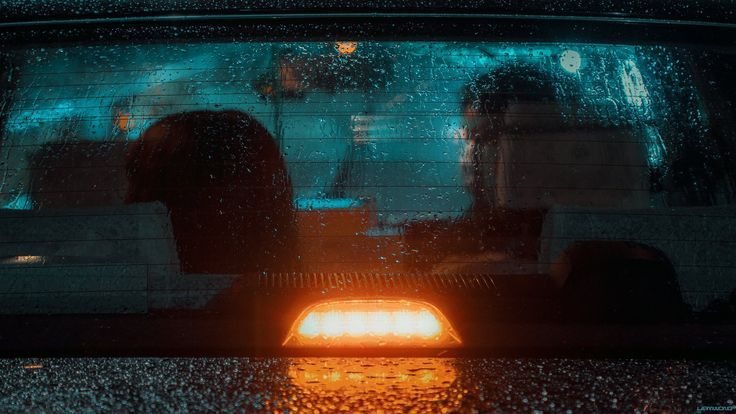 Figures through a rain-soaked rear window, brake light glowing