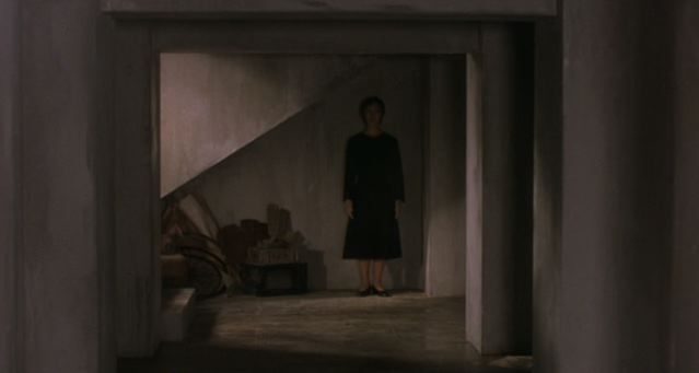 A still figure standing beneath a staircase
