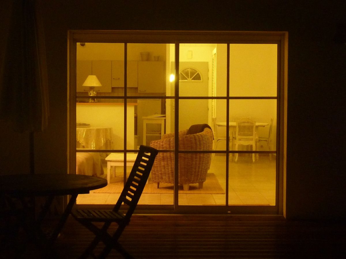 Warm yellow interior seen through a sliding glass door at night